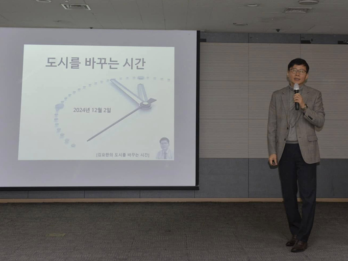‘도시를 바꾸는 시간’ 슬라이드 앞에서 마이크를 들고 강연하는 모습